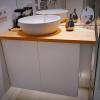 Mueble de baño con puertas sistema push, sin tirador, lacadas en blanco con encimera en pino macizo y luces leds por debajo