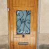 Puerta de entrada en Melis con ventana practicable y reja en forja negra