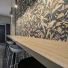 Decoración zona office con barra de madera natural, iluminación suspendida, papel pintado