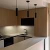 Cocina en U con muebles de madera, encimera porcelánica y lámparas colgantes en Reus - LUCMAR URBA