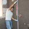 Obra de albañilería en Madrid: enfoscado de la pared y comprobación del nivel con regla.