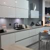 Cocina reformada en Madrid: muebles blancos, frente en gris, encimera y barra de madera.