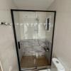 Reforma de baño: mampara de ducha con perfilería negra y revestimientos cerámicos.