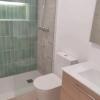 Reforma de baño: ducha con revestimiento verde, sanitario y mueble de lavabo.
