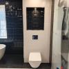 Baño contemporáneo con inodoro suspendido, cisterna empotrada y combinación de revestimientos decorativos.