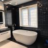 Baño de diseño moderno con bañera exenta, revestimientos decorativos en negro y acabados elegantes.